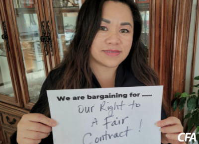 Vang Vang holds a sign saying "we are bargaining for our right to a fair contract!"