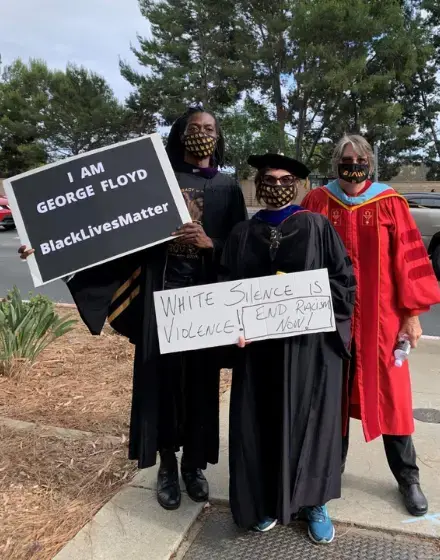 CFA members join others protesting the police shooting of George Floyd wearing their caps and gowns and holdingsigns.