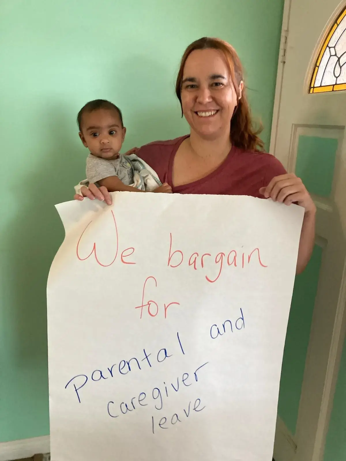 CFA member poses with child and holding a sign that says "We bargain for parental leave and caregiver leave."