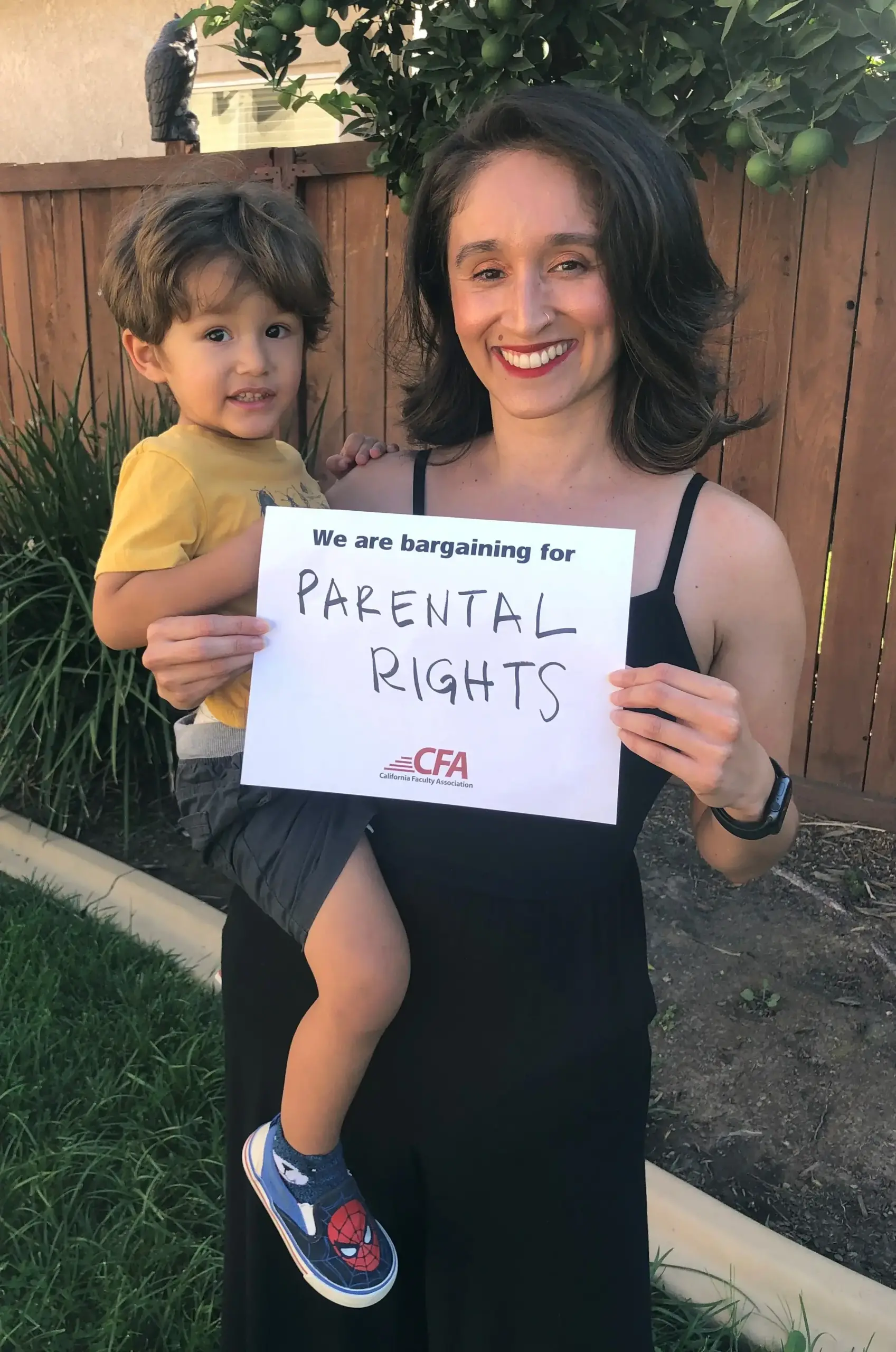 CFA member Alma Itzé Flores holds her baby and a sign reading "CFA is bargaining for parental leave."
