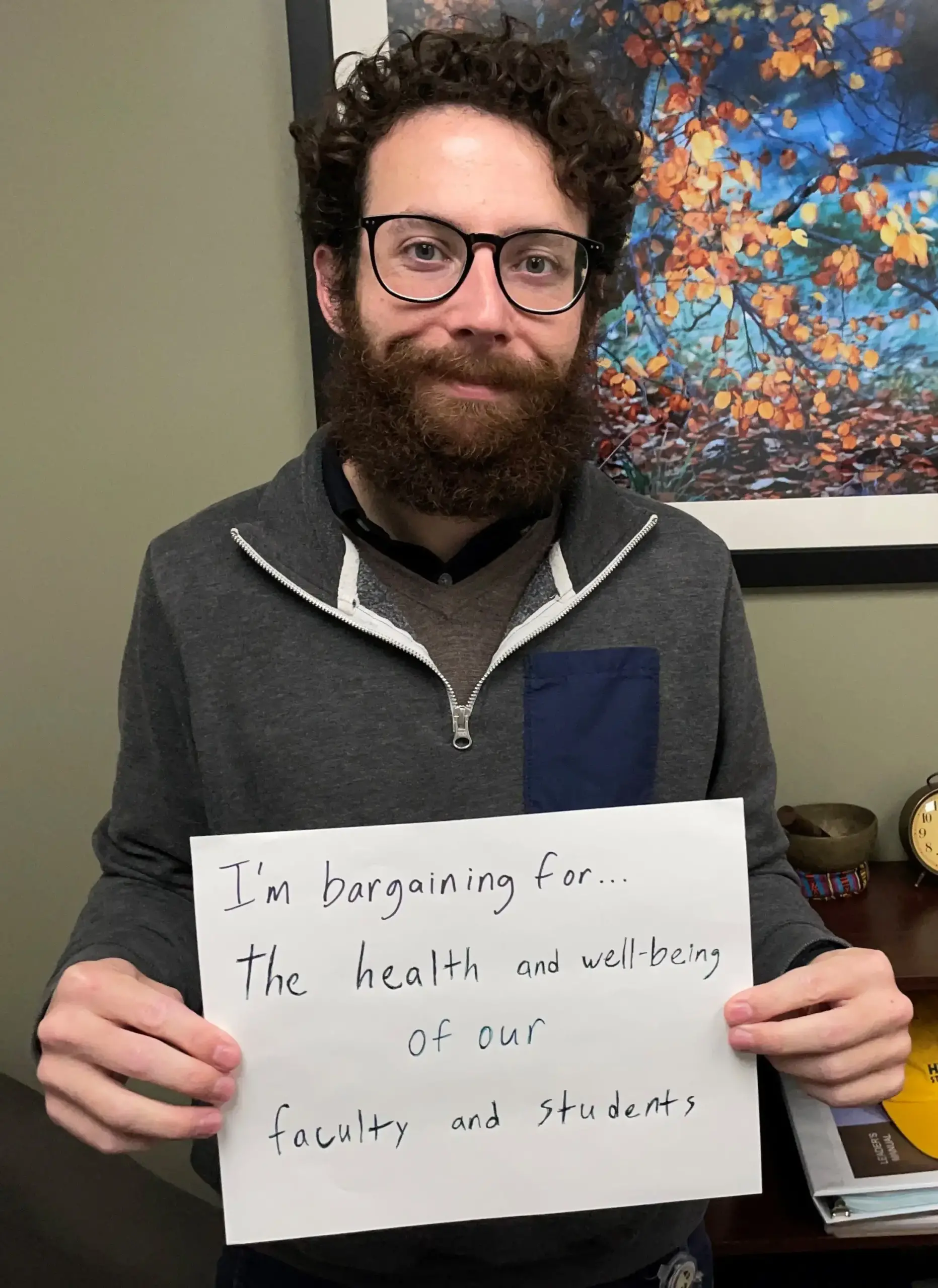 Image of person standing with a sign on a piece of paper with green background