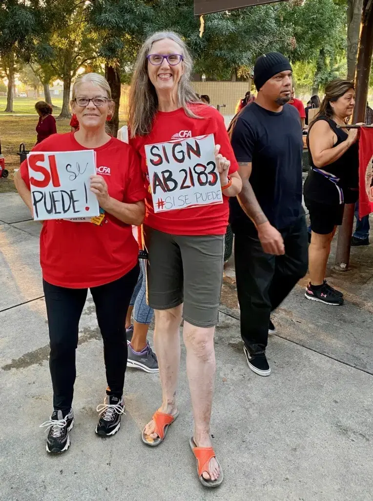 Two women holding signs and smiling for a picture