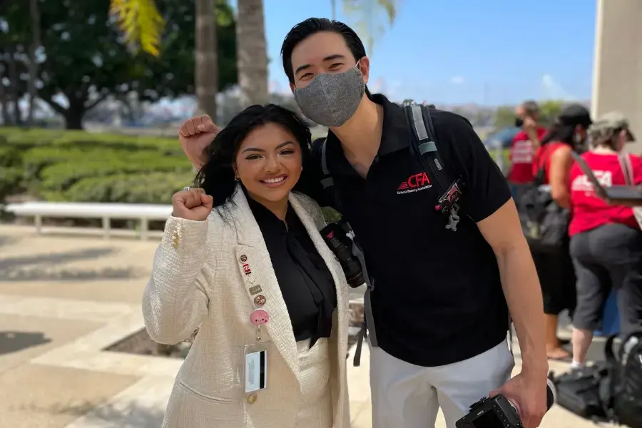 Two people pose for a photo with fist on the air.