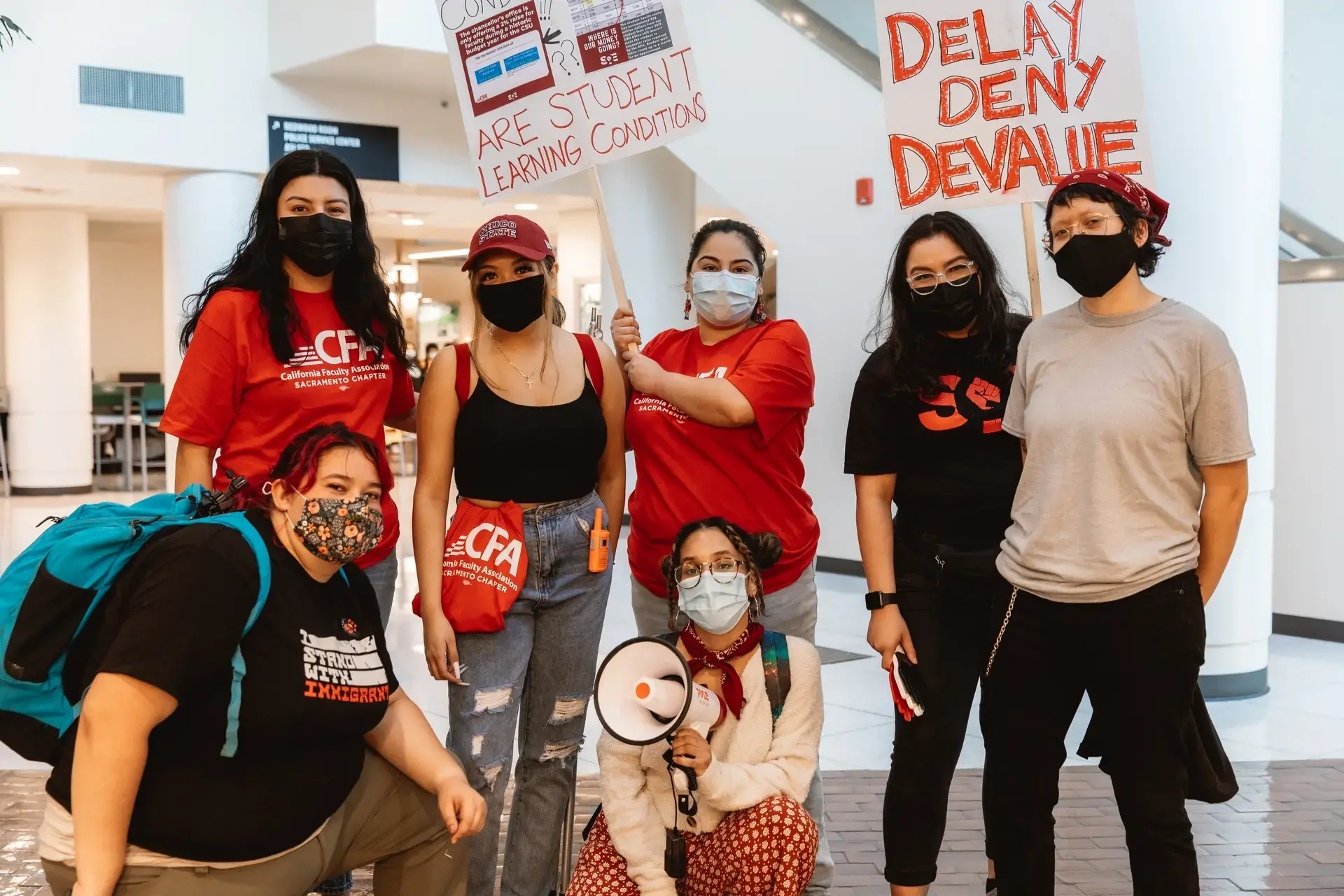 A group of people wearing masks and holding signs