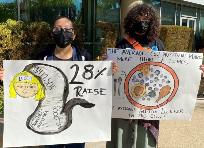 Two students standing outside with signs.