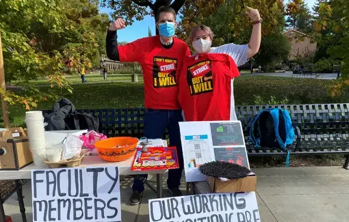 Two people with their fists raised behind a strike information table