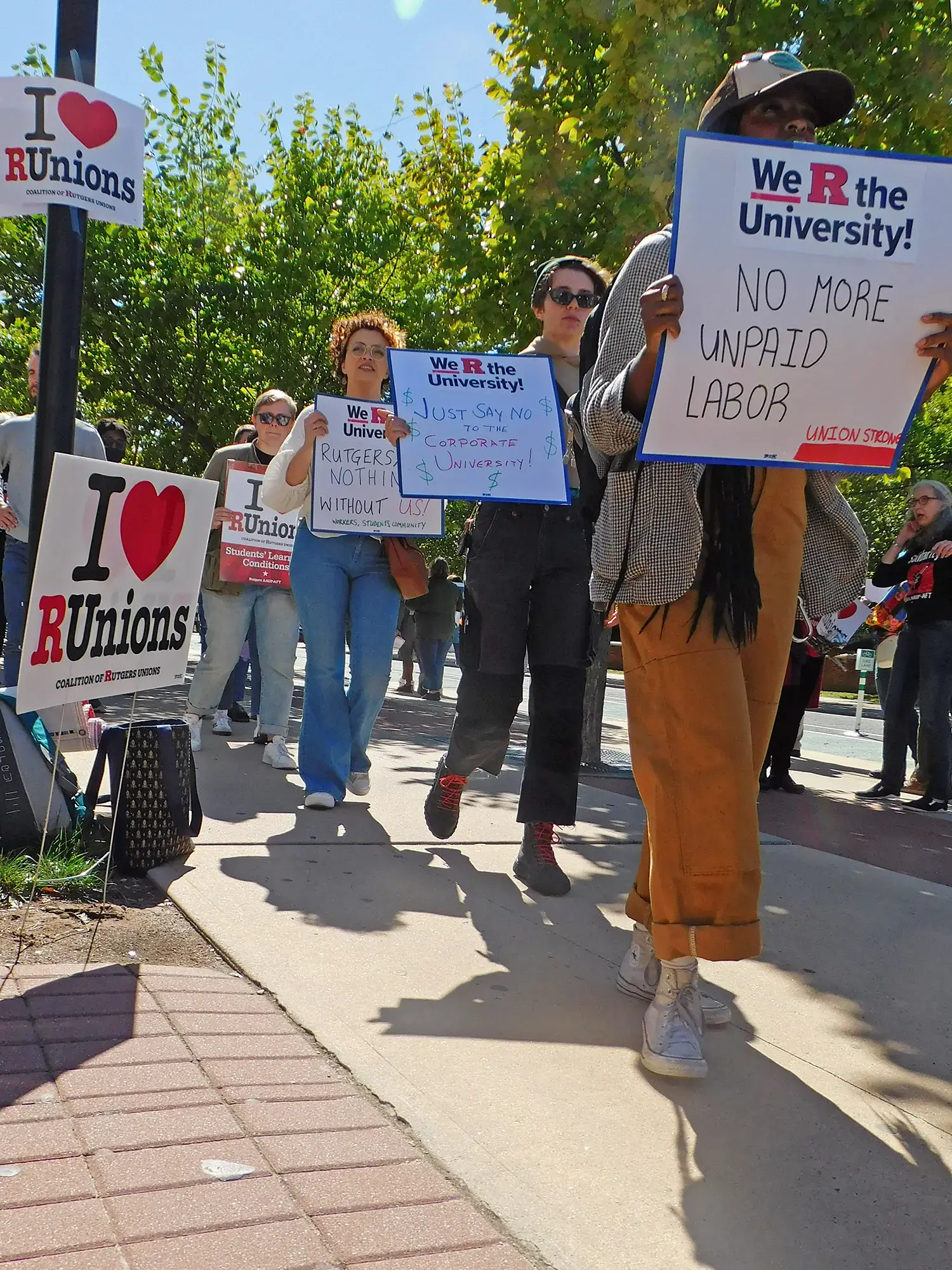 A group of people at a rally outdoors with a sign.