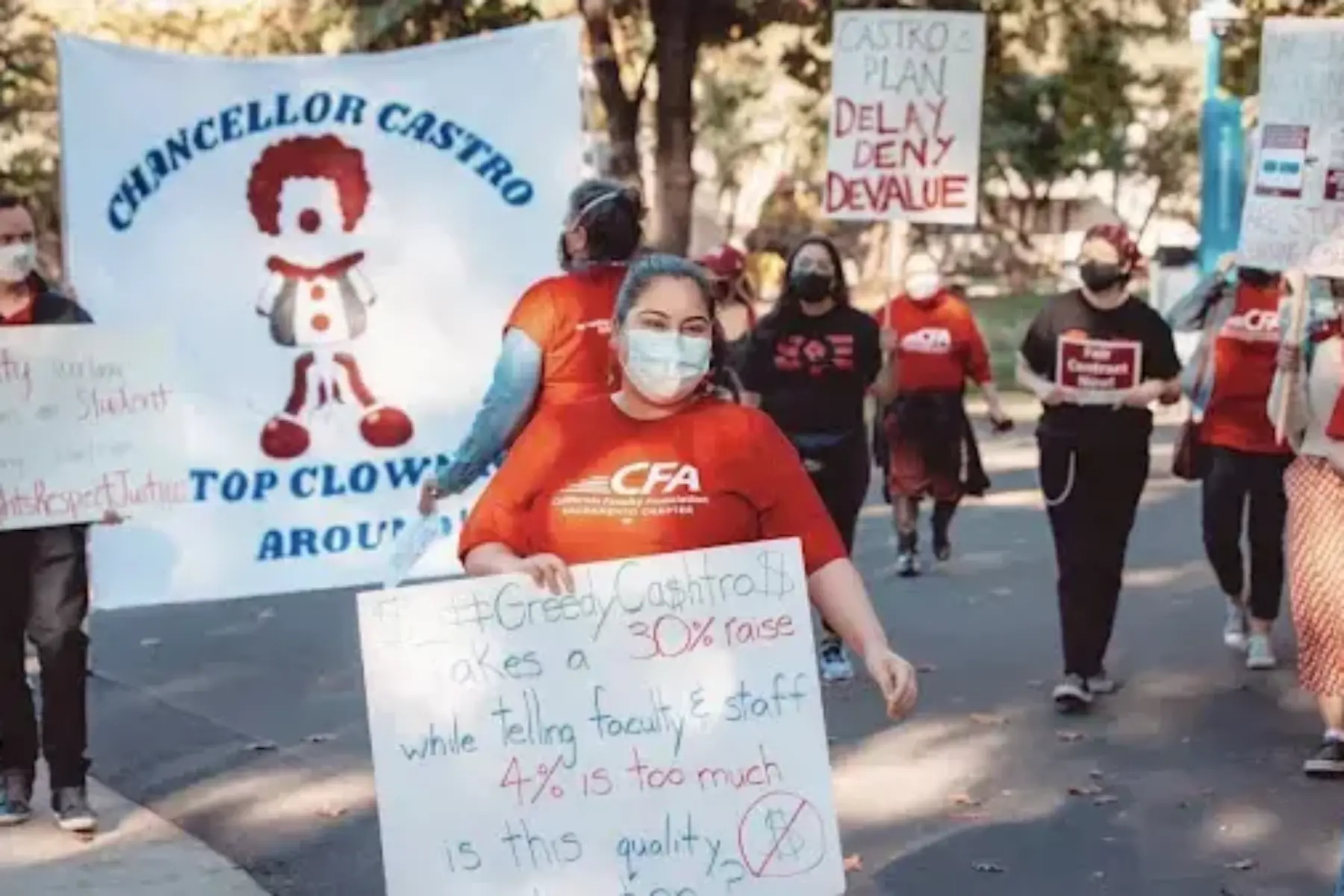 Student holding a sign marching outdoors