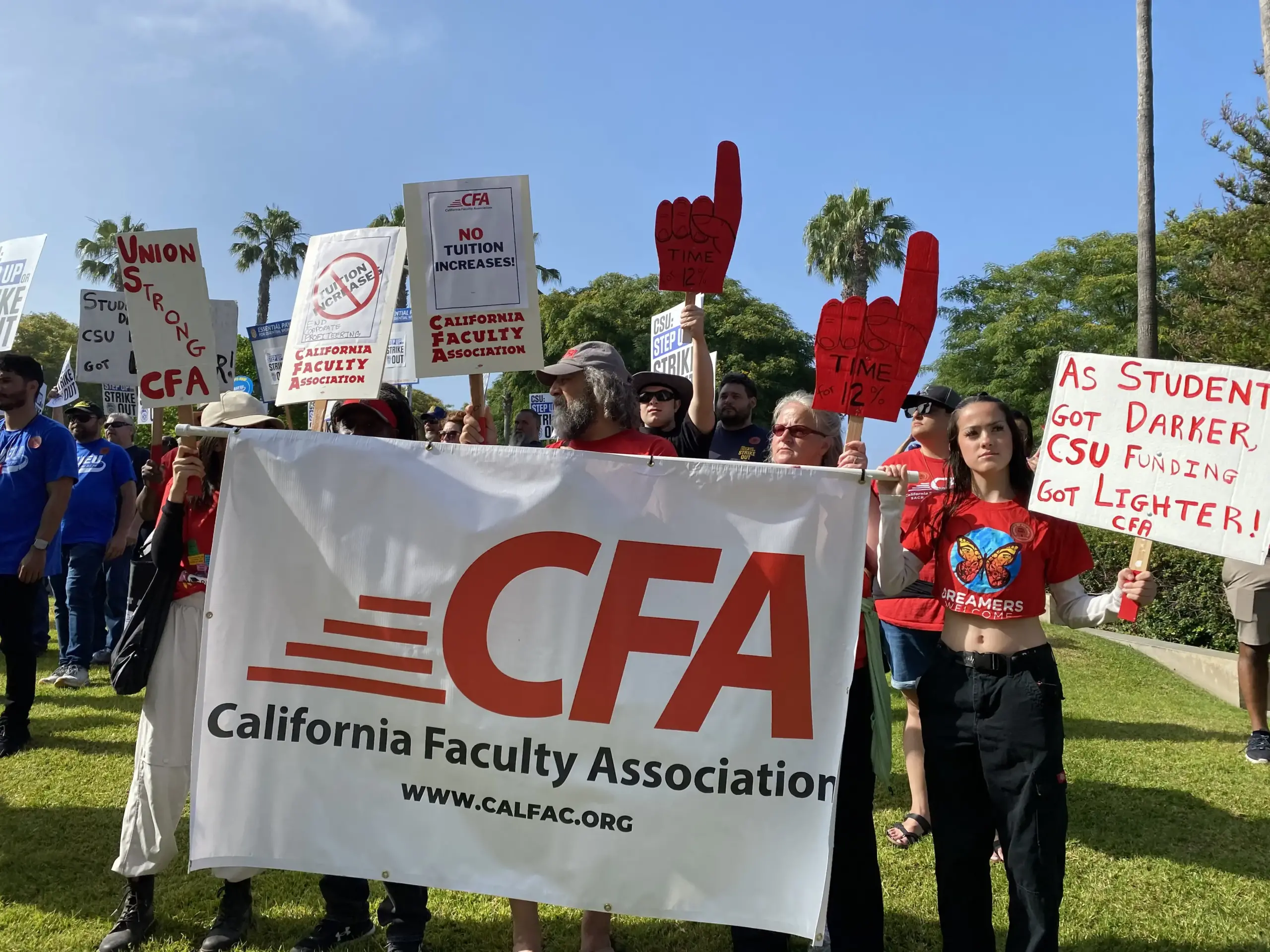 Members hold a white banner with a red logo reading CFA. A woman holds a white sign with red text that reads "As Students Got Darker, CSU Funding got Lighter! CFA"