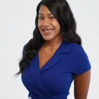 woman in a blue dress and black hair poses for a photo