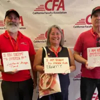 Three people hold signs saying that they are ready to strike for.