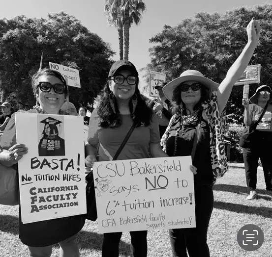 Three women outside holding signs at a rally