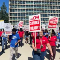 A crowd of people outdoors for a rally with signs and pickets.