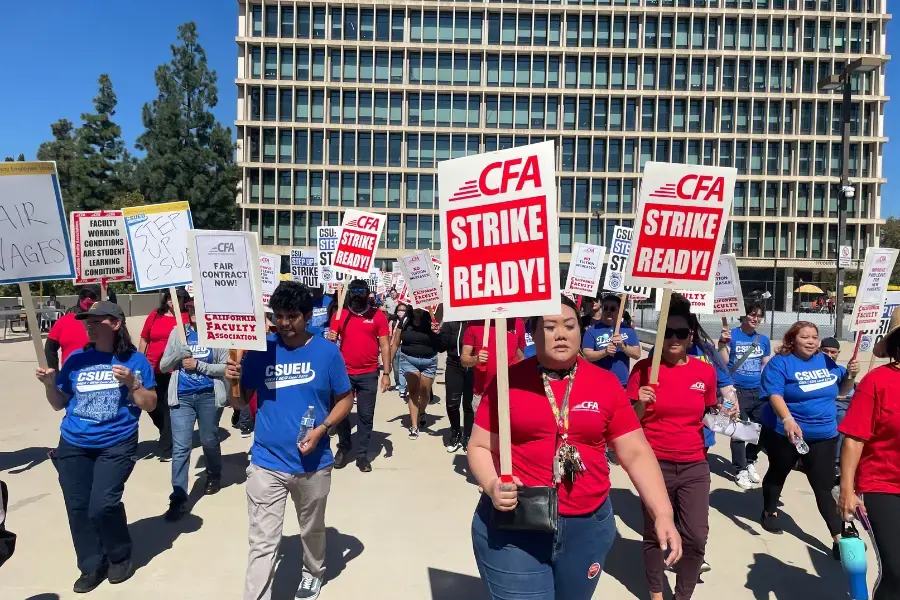 A crowd of people outdoors for a rally with signs and pickets.