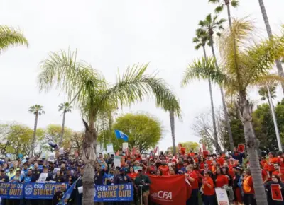 Hundreds of faculty, staff, and students are gathered together and chanting at a rally.