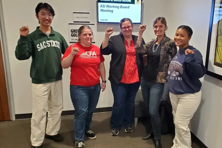 A couple of students and a few faculty raise their fists.