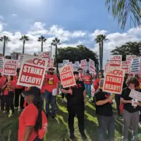 People are gathered together with red shirts and picket signs.