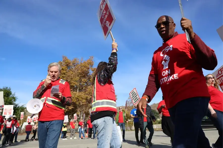 People wearing red shirts are holding up signs and marching in a circle.