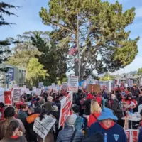 A large crowd fathers together in San Francisco with picket signs.