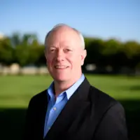 SD Candidate Jerry McNerney posing by a grassfield with blue collard shirt