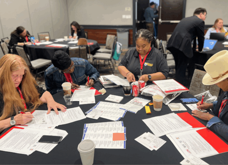 A group of folks at a table writing postcards to nonmembers asking them to join CFA.