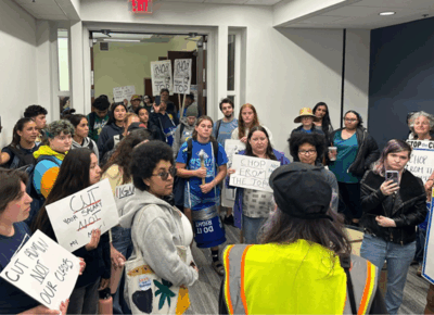 Students, faculty and staff in a hallway with signs.