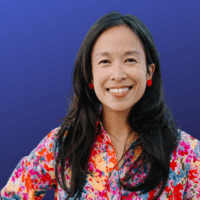 A woman with black hair in a floral dress poses for a picture