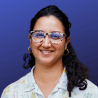 a woman in glasses with curly hair in a light floral shirt
