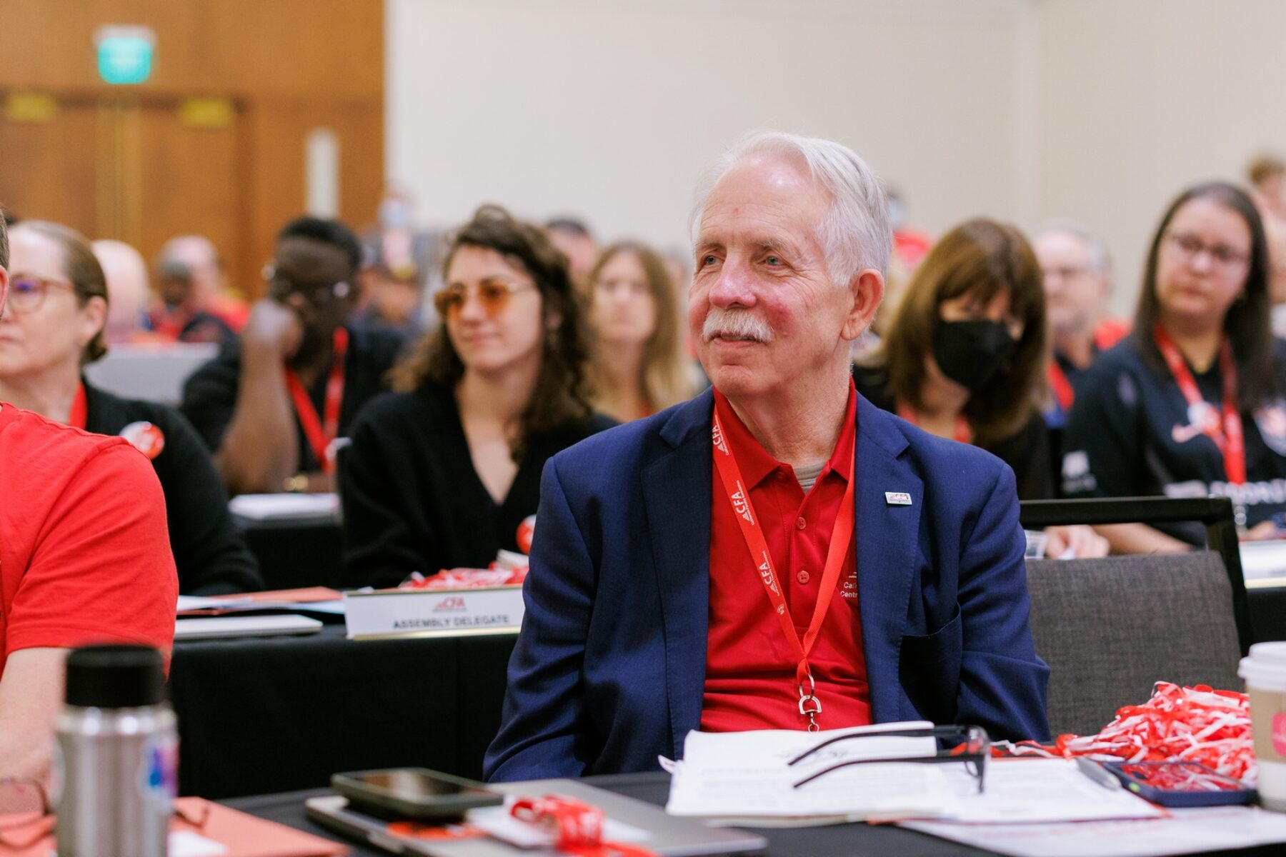 Man in red shirt and blue blazer smiling at a conference