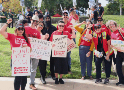 A group of people gather together wearing red shirts and holding up signs.