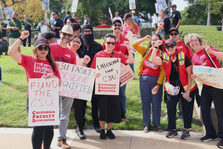A group of people gather together wearing red shirts and holding up signs.