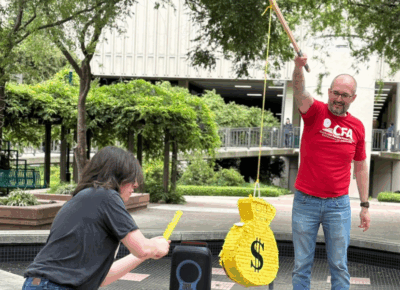 Person hitting a pinata labelled as a money bag