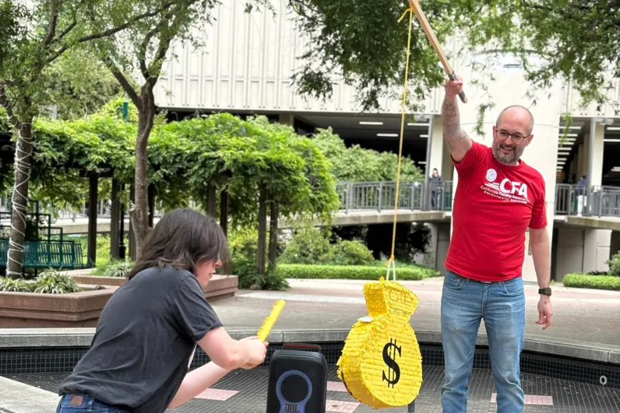 Person hitting a pinata labelled as a money bag