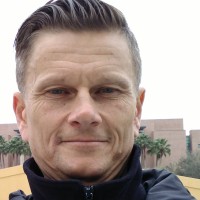Headshot of Mike Kohout, a professor of Geology at CSU San Bernardino, standing outside. Wearing a dark jacket.