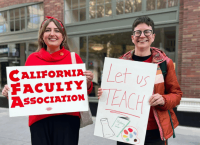 two people holding up signs outside of a building