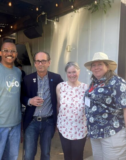 A group of four people standing outside posing for a picture.
