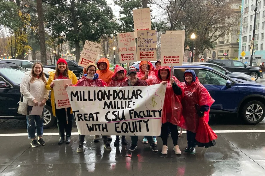 a group of people gather together to hold a large sign in the rain.