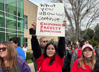 a group of people stand together with one of them holding up a sign.