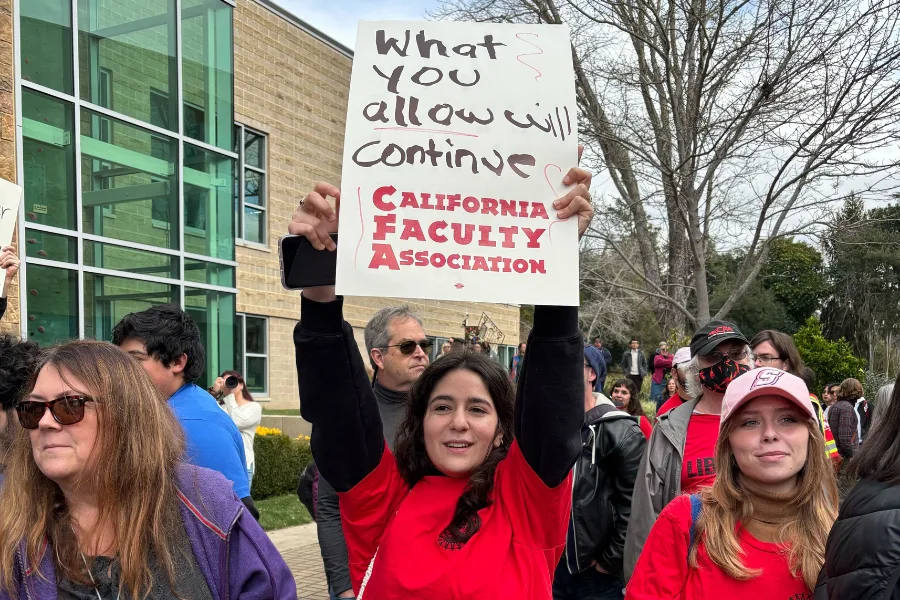 a group of people stand together with one of them holding up a sign.