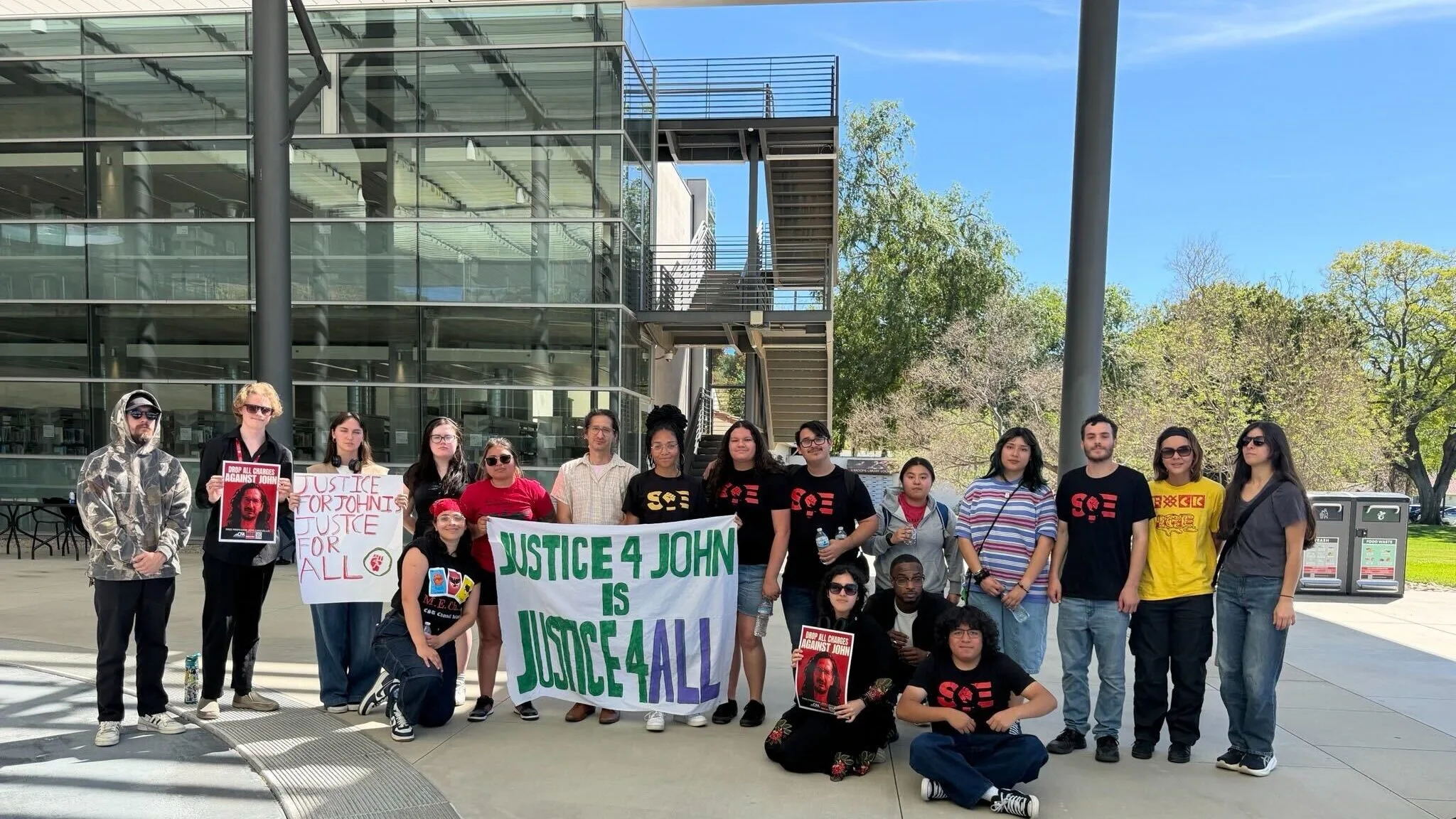 people standing outside with a banner supporting John Caravello