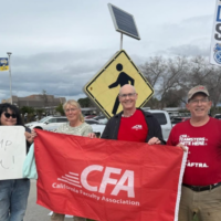 Four people with signs and flags by a road