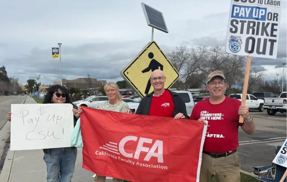 Four people with signs and flags by a road