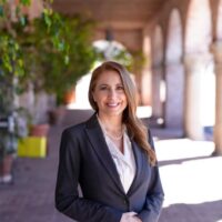 candidate in black suit jacket, white blouse, and long hair