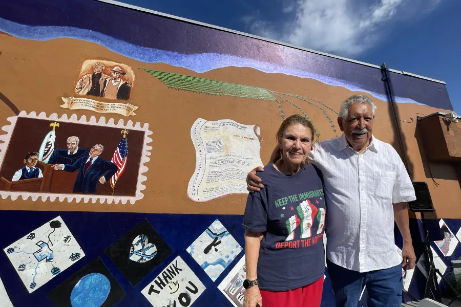 Two people infront of a mural.