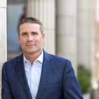 Candidate with blue suit jacket leaning on a pillar