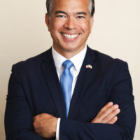 AG in black suit and blue tie with arms crossed