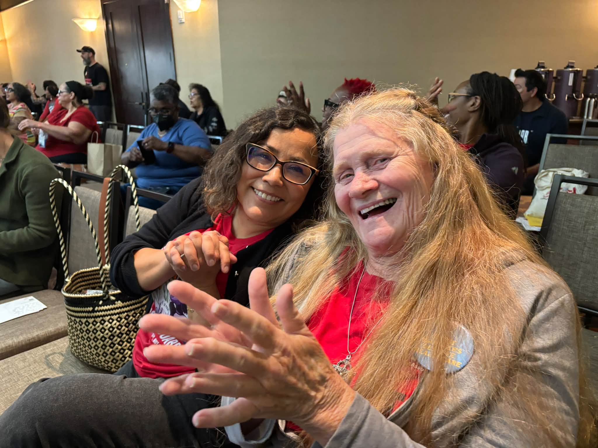 Two woman sit together and share smiles.