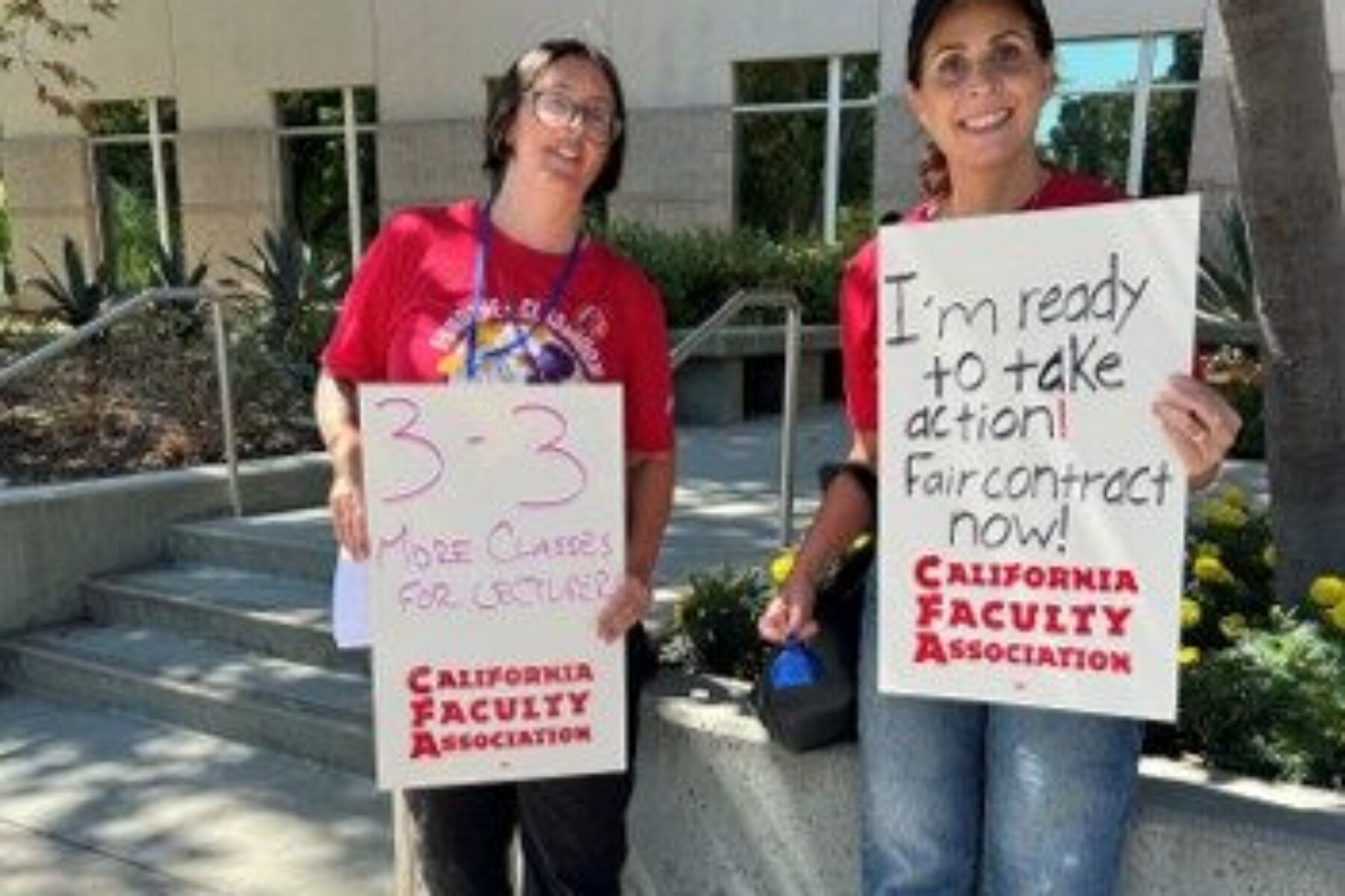 Two CFA members hold signs asking for a fair contract.