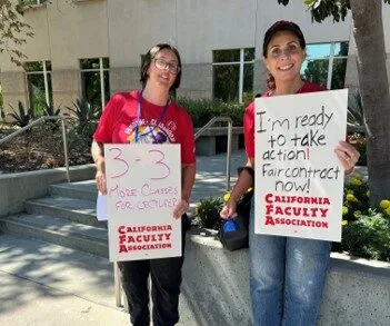 Two CFA members hold signs asking for a fair contract.