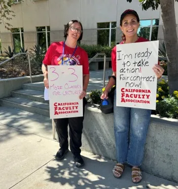 Two CFA members hold signs asking for a fair contract.